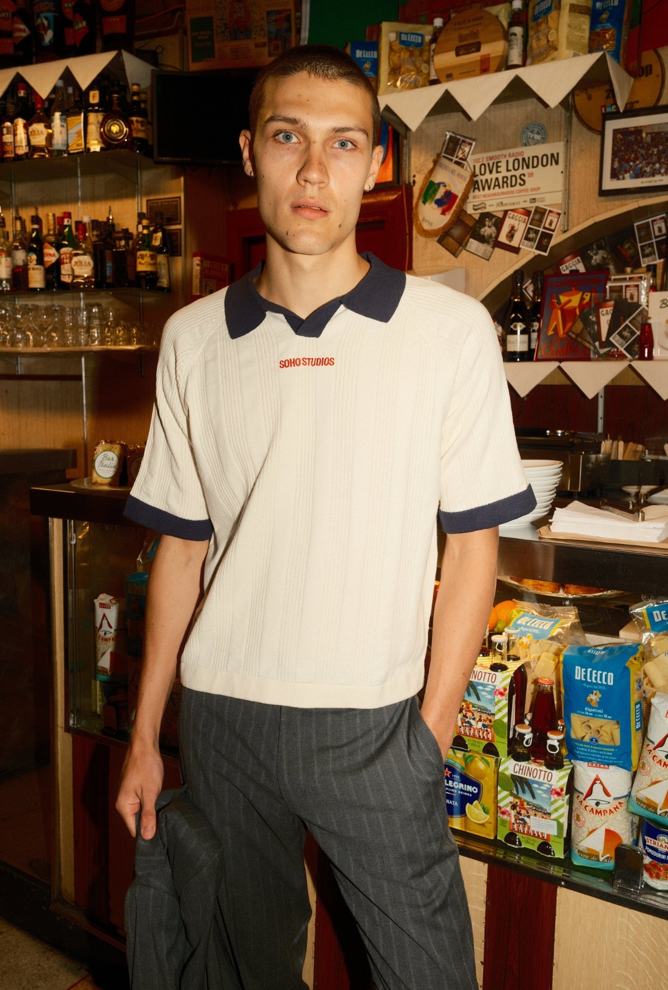 Man standing in a bar with drinks and snacks on shelves