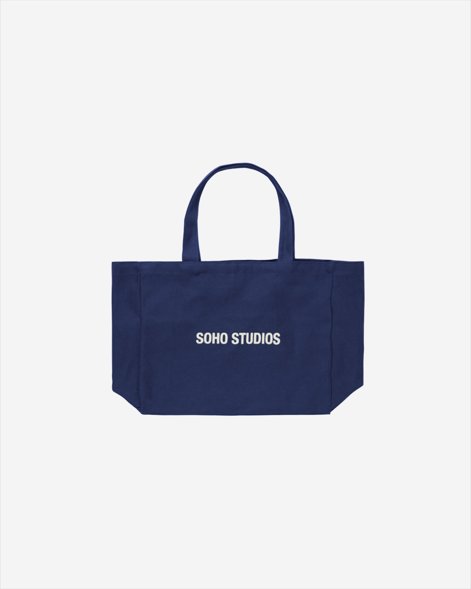 A navy blue tote bag with a screen-printed 'Soho Studio' logo, featuring two handles and a visible brand name.