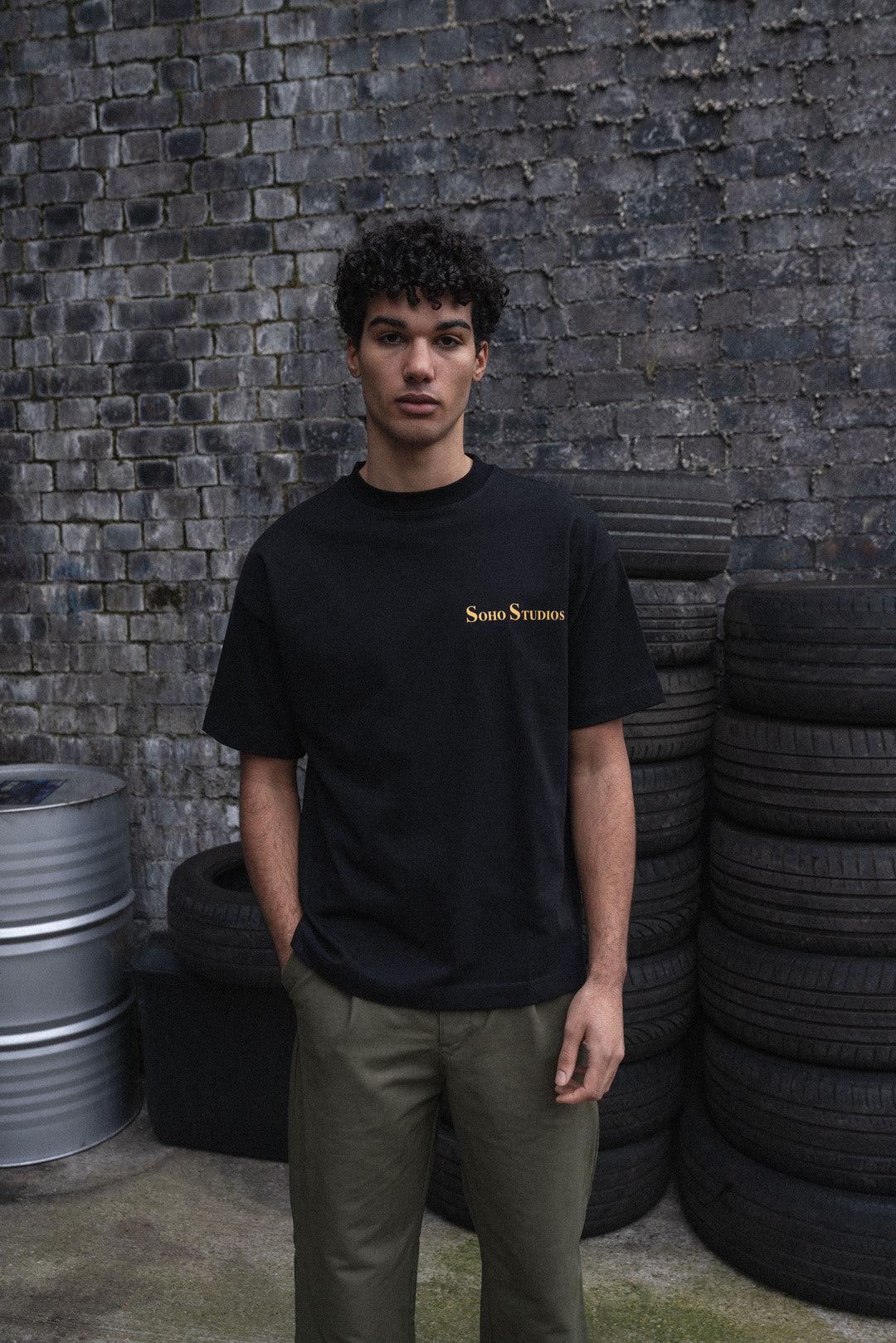 Black 'Soho Studios' t-shirt with yellow screen print on the front.