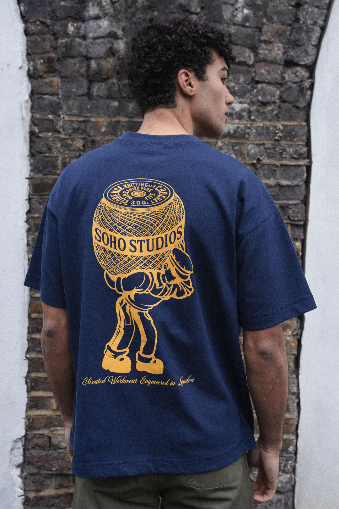 men wearing A navy blue t-shirt with a yellow and gold screen printed logo of a stylized character on the back.