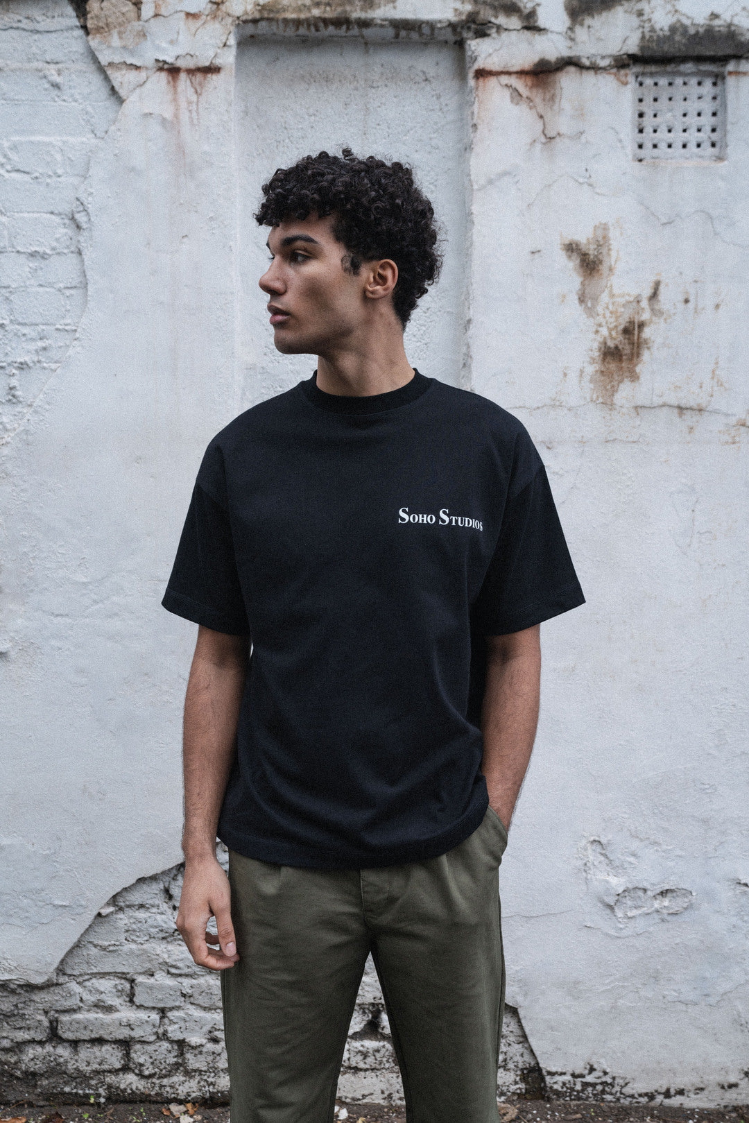 Men Wearing Soho Studio BLACK 'GRAFTER' T-SHIRT with a SOHO Studio logo print on front.