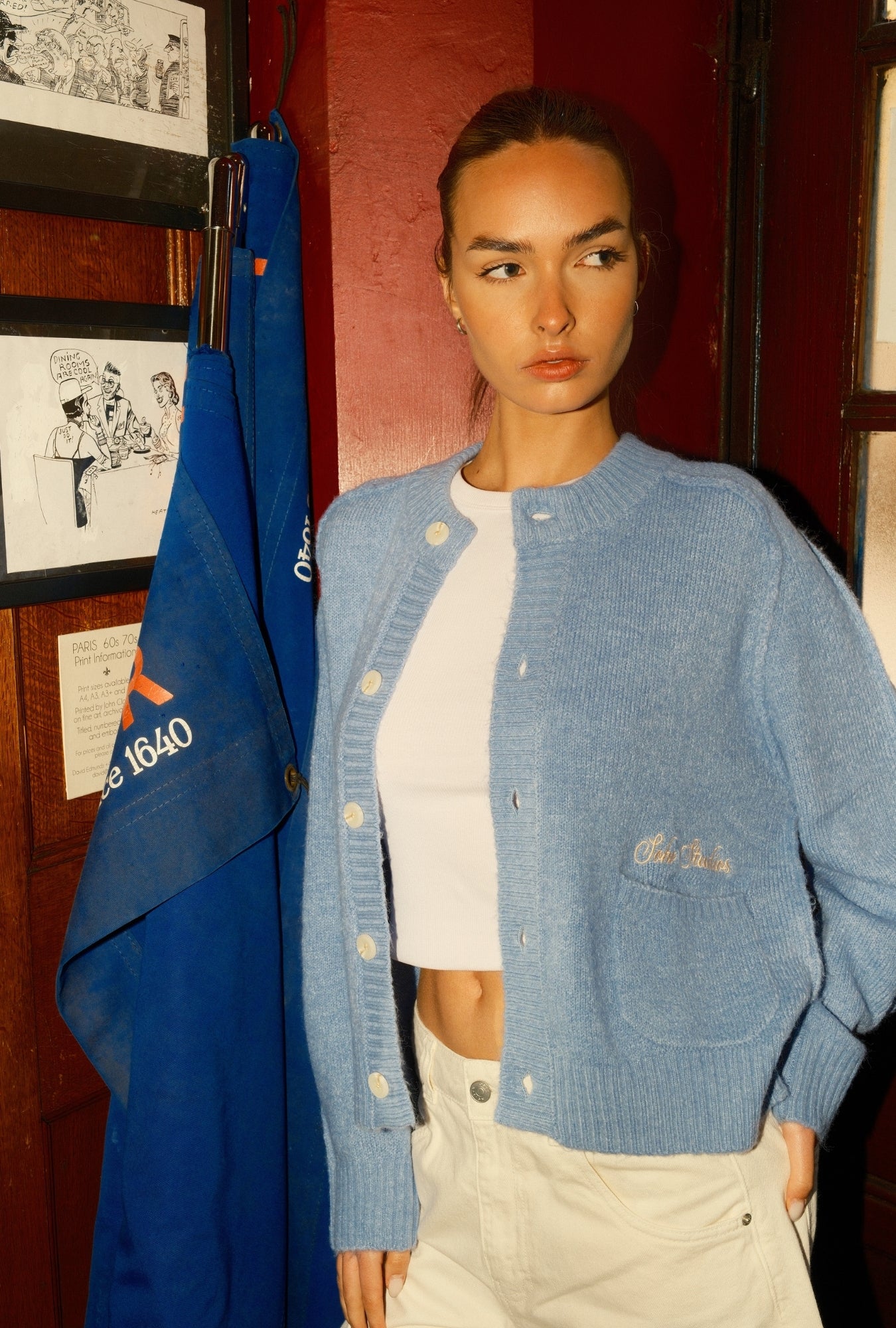 Woman wearing a blue cardigan over a white top in an indoor setting