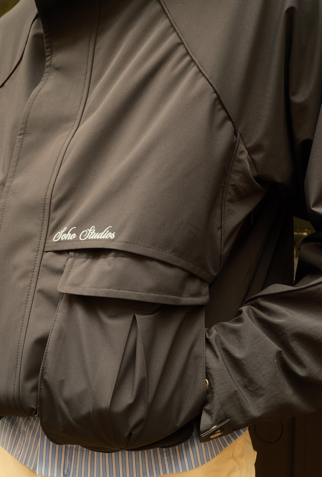 Close-up of a dark jacket with a brand logo on a striped surface