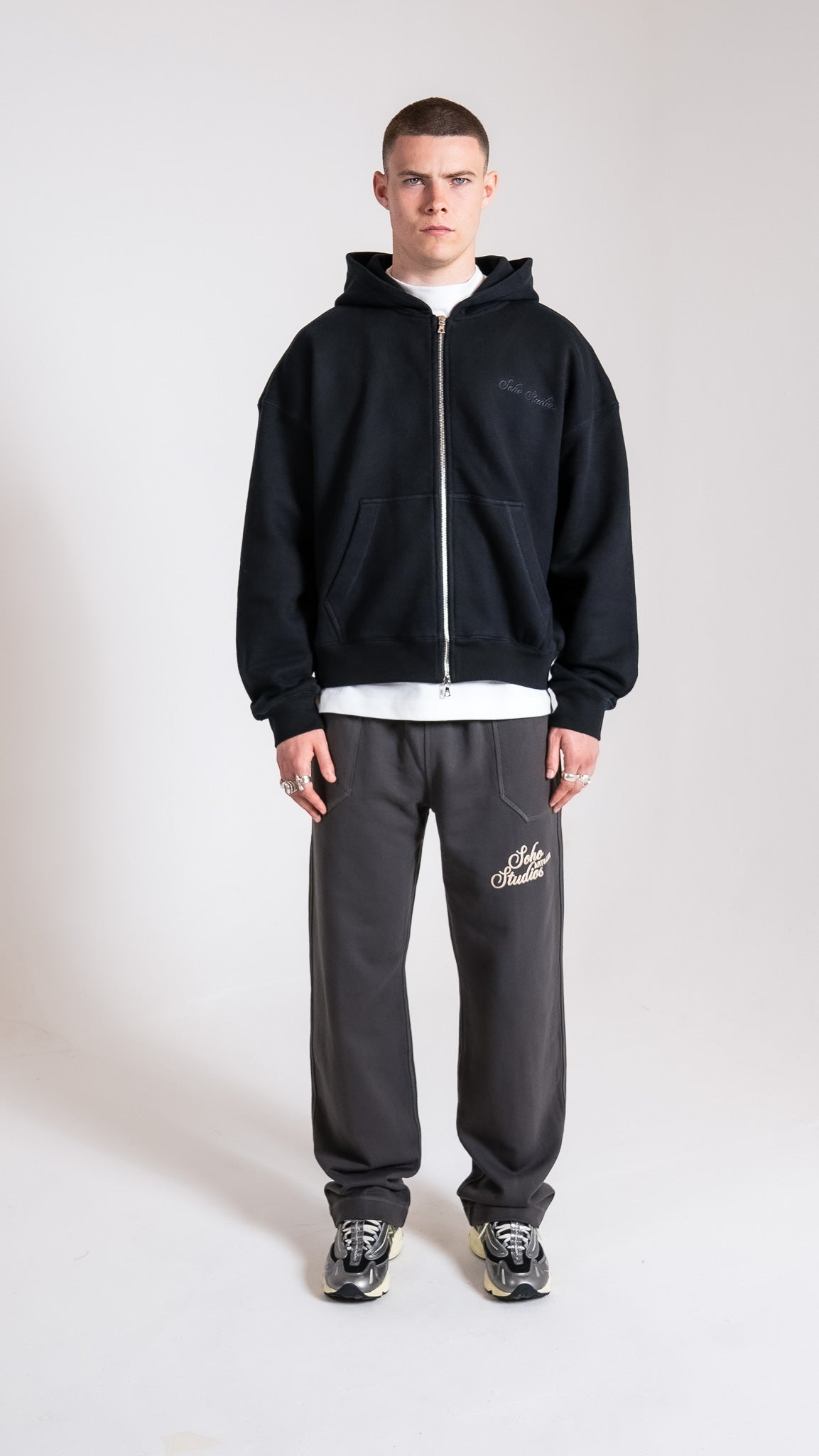 Man wearing black Soho Studios zip hoodie with grey logo sweatpants