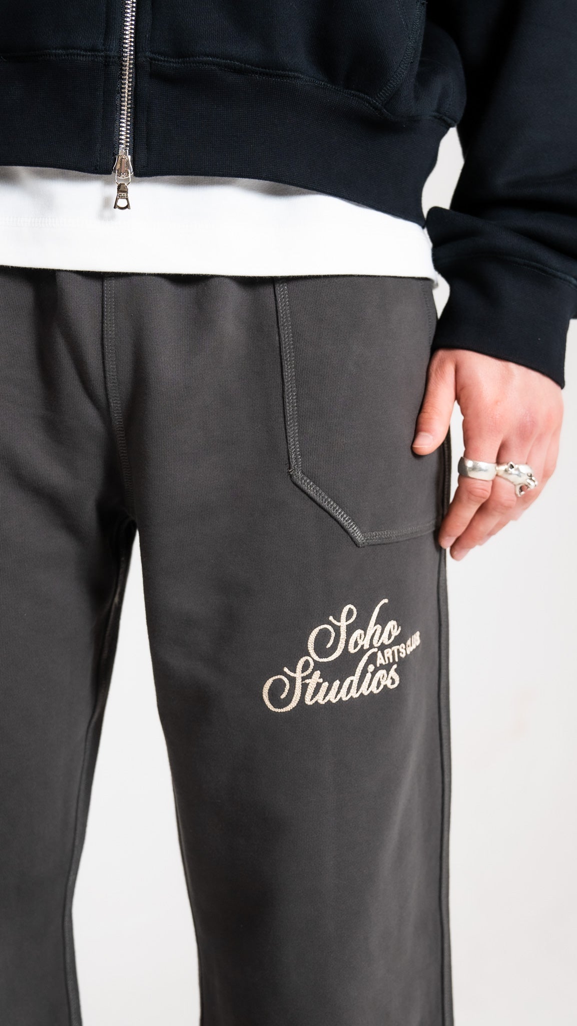 Man wearing black Soho Studios zip hoodie with grey logo sweatpants