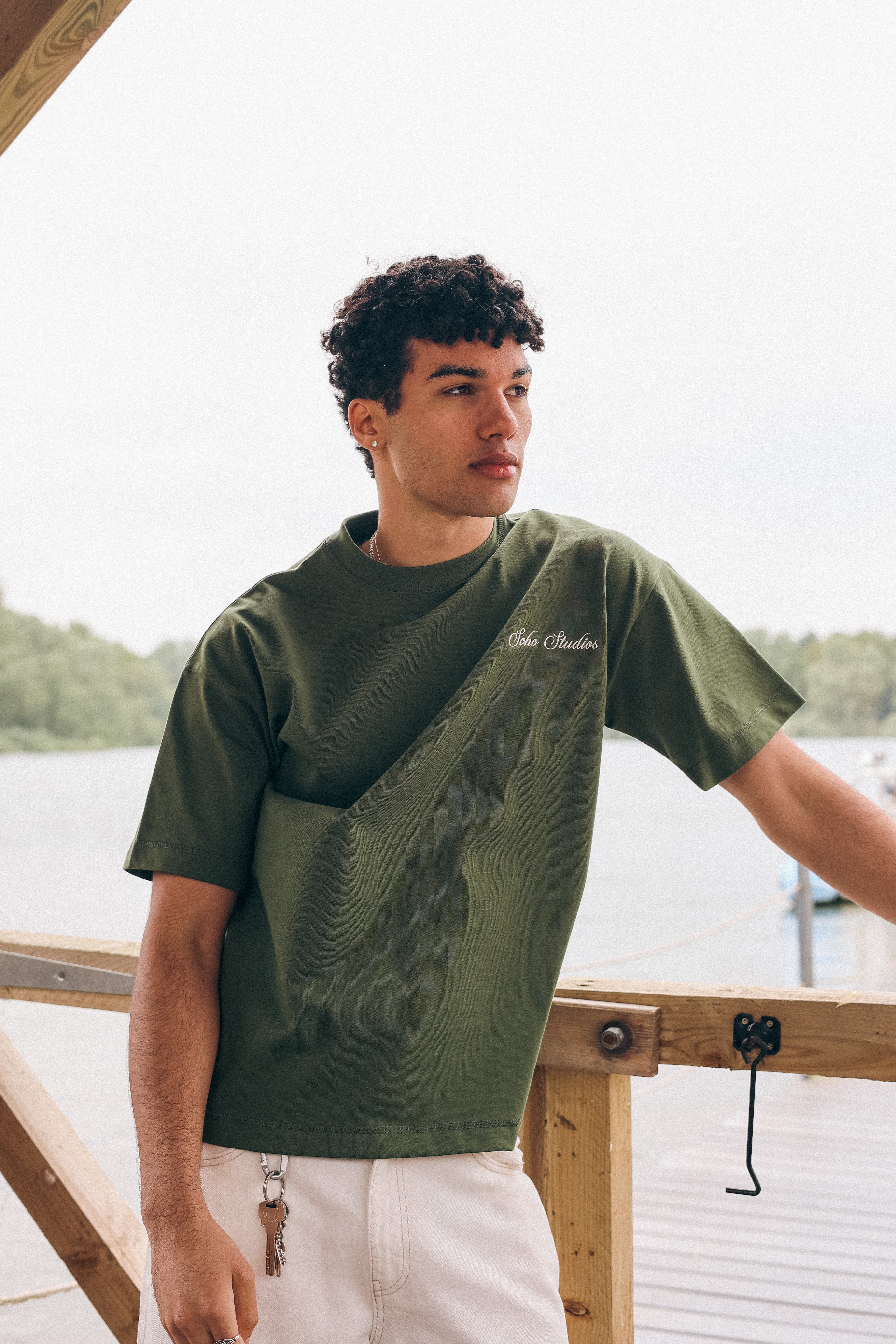 Man wearing a green t-shirt with text, standing by a body of water.