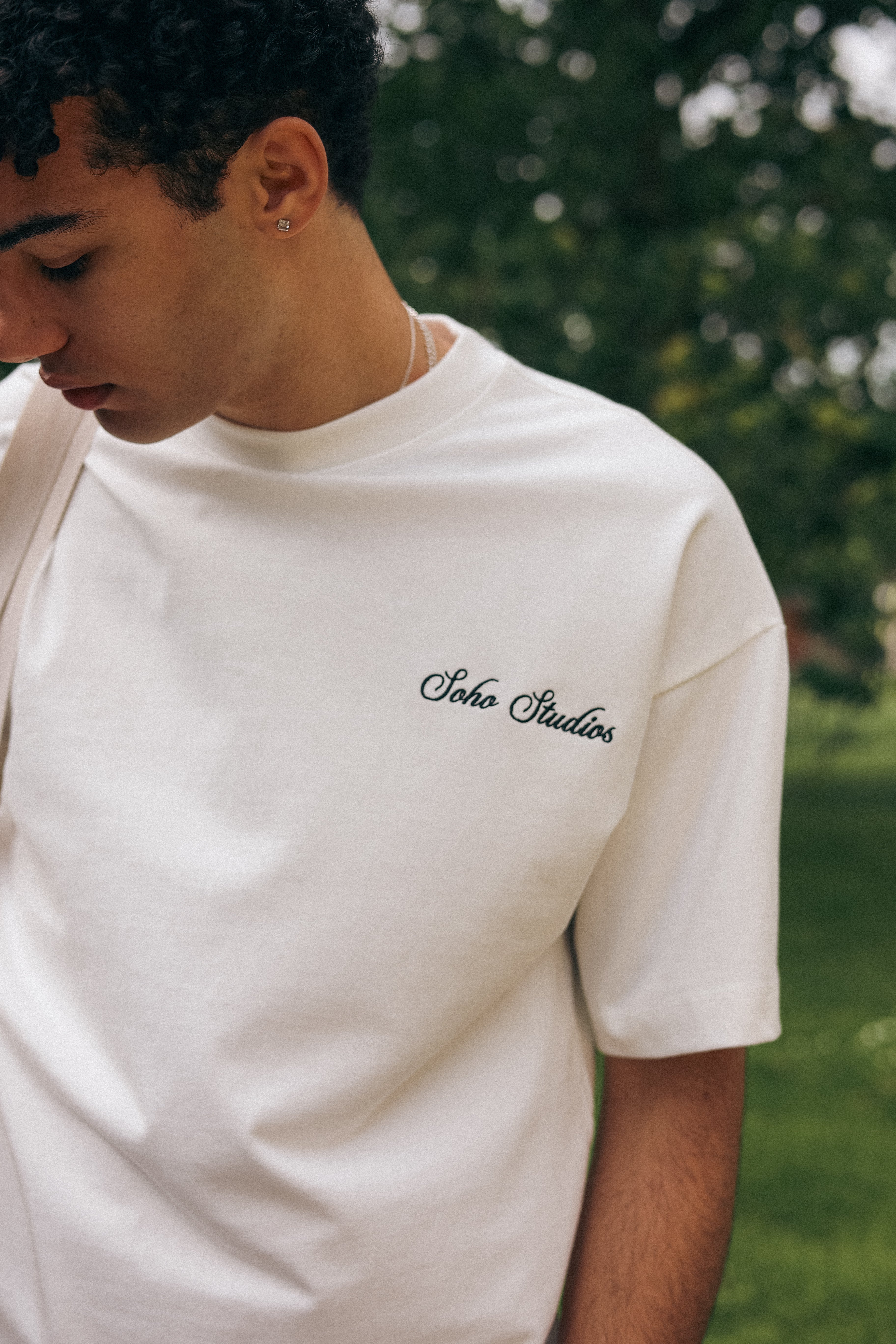 Person wearing a white t-shirt with 'Soho Studios' logo outdoors