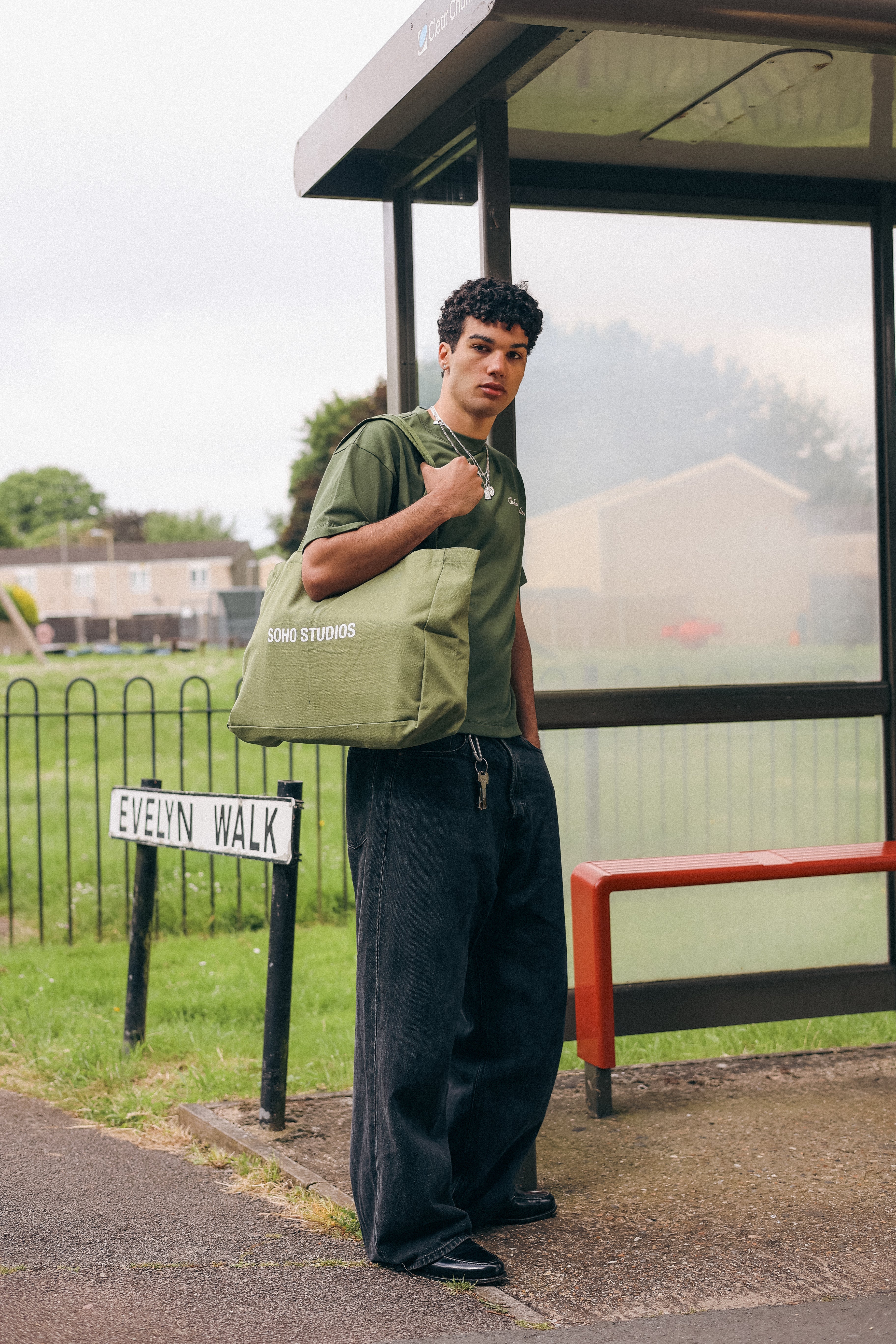 Men carrying OLIVE GREEN tote bag with 'SOHO STUDIOS' printed in black on the front.