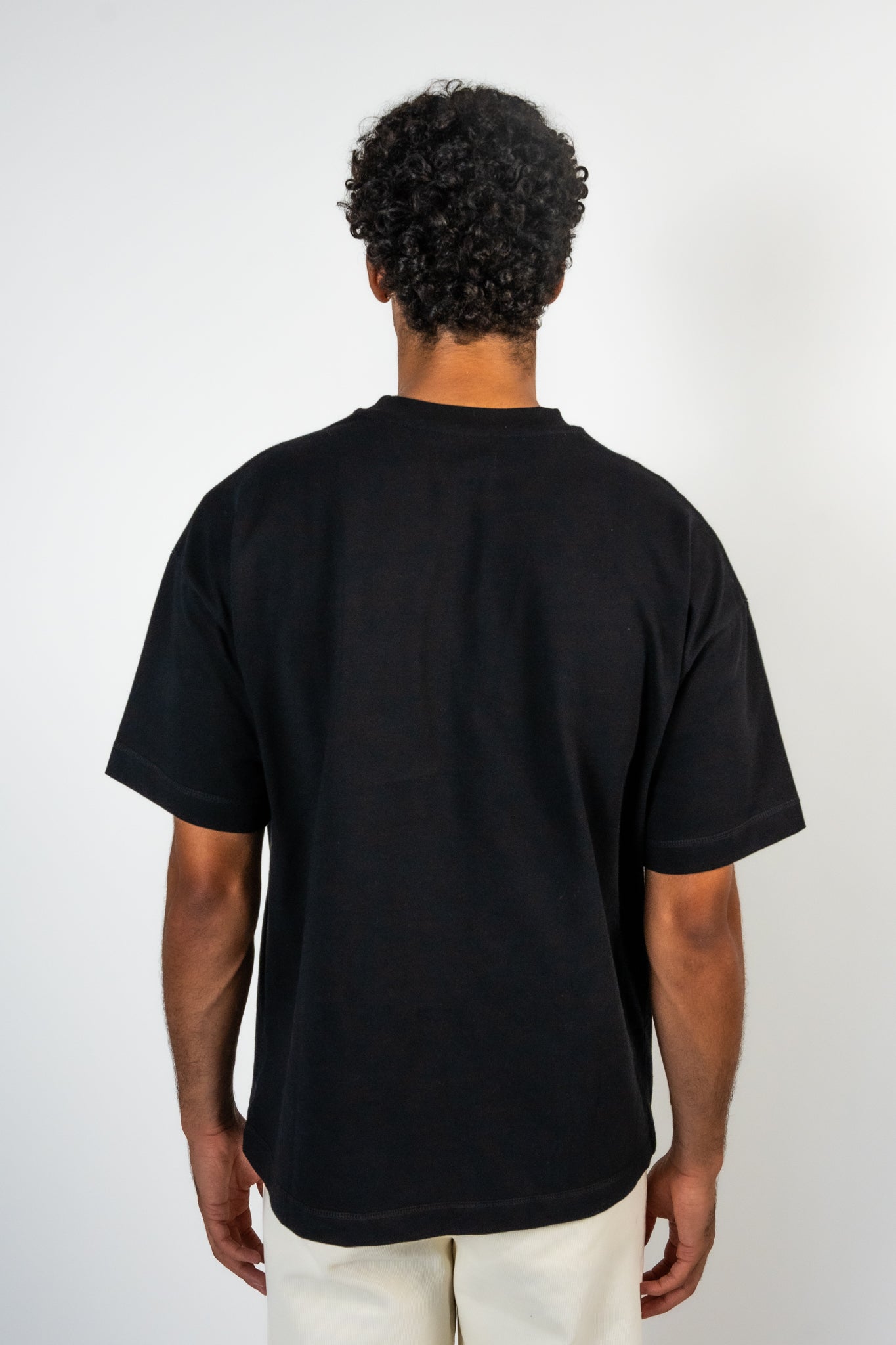 Men wearing a black t-shirt with striped detailing showing his back of t shirt. 