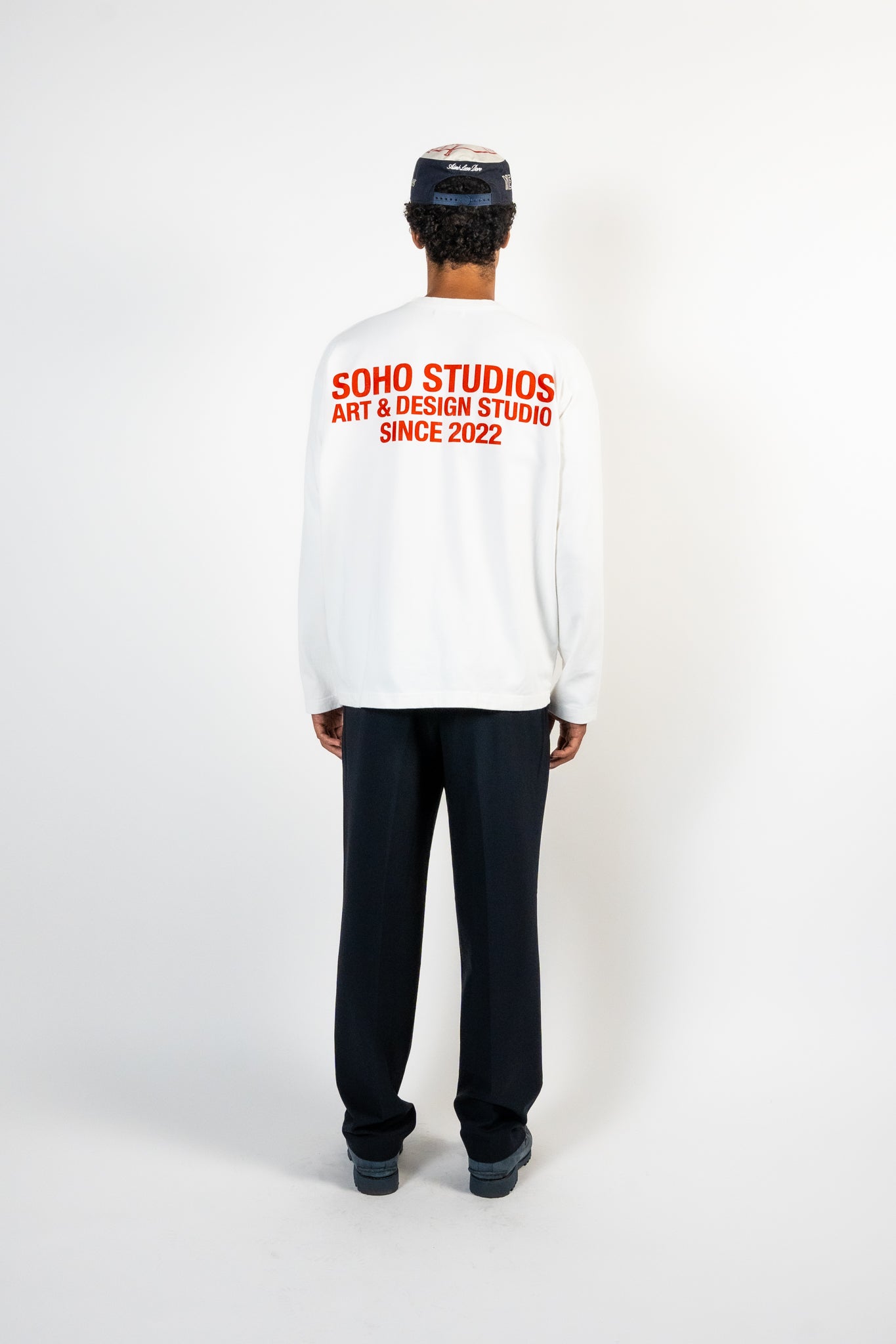 men wearing white long sleeve Soho Studios graphic shirt with orange back print
