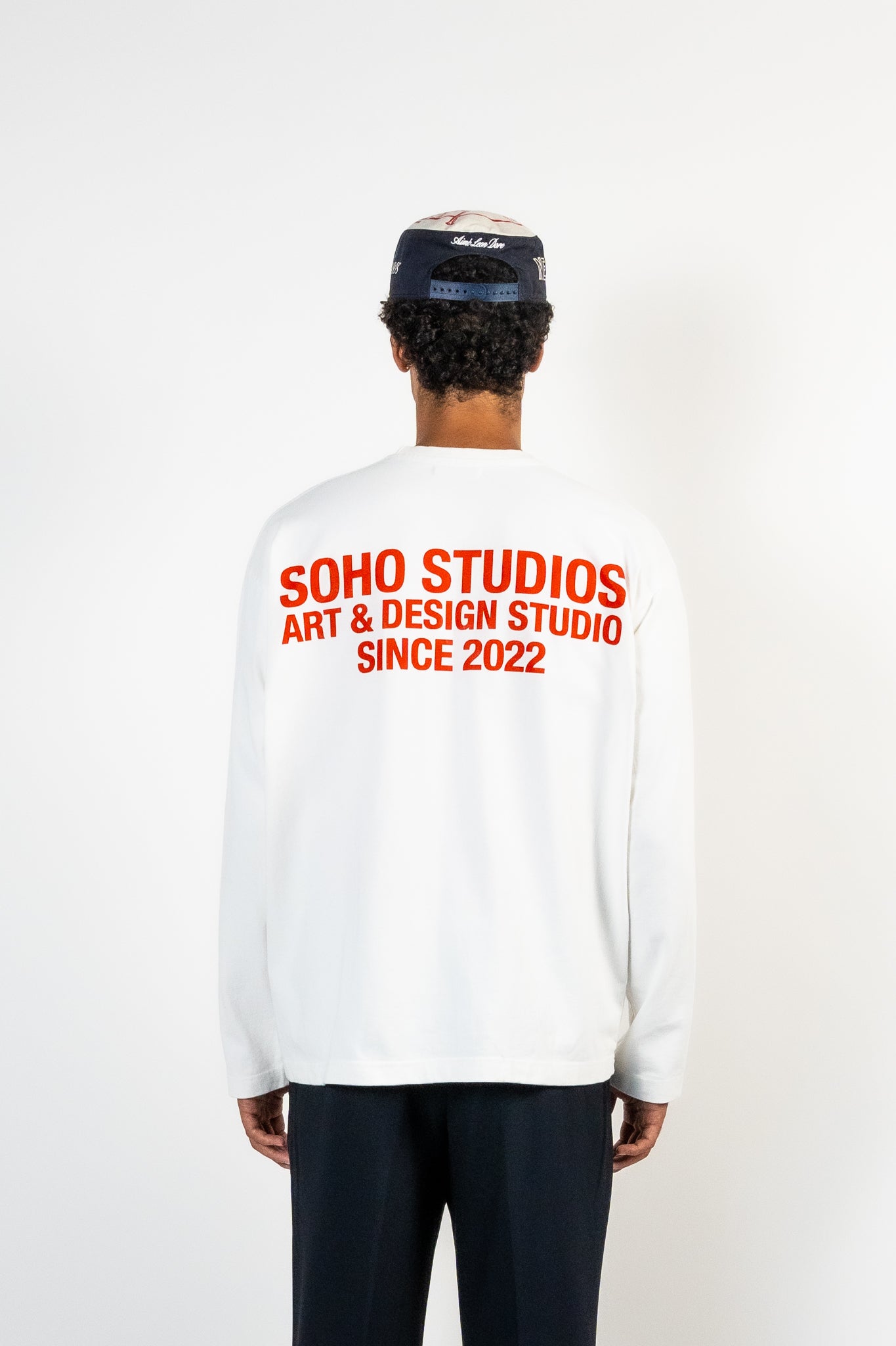 men wearing White long sleeve Soho Studios graphic shirt with orange back print