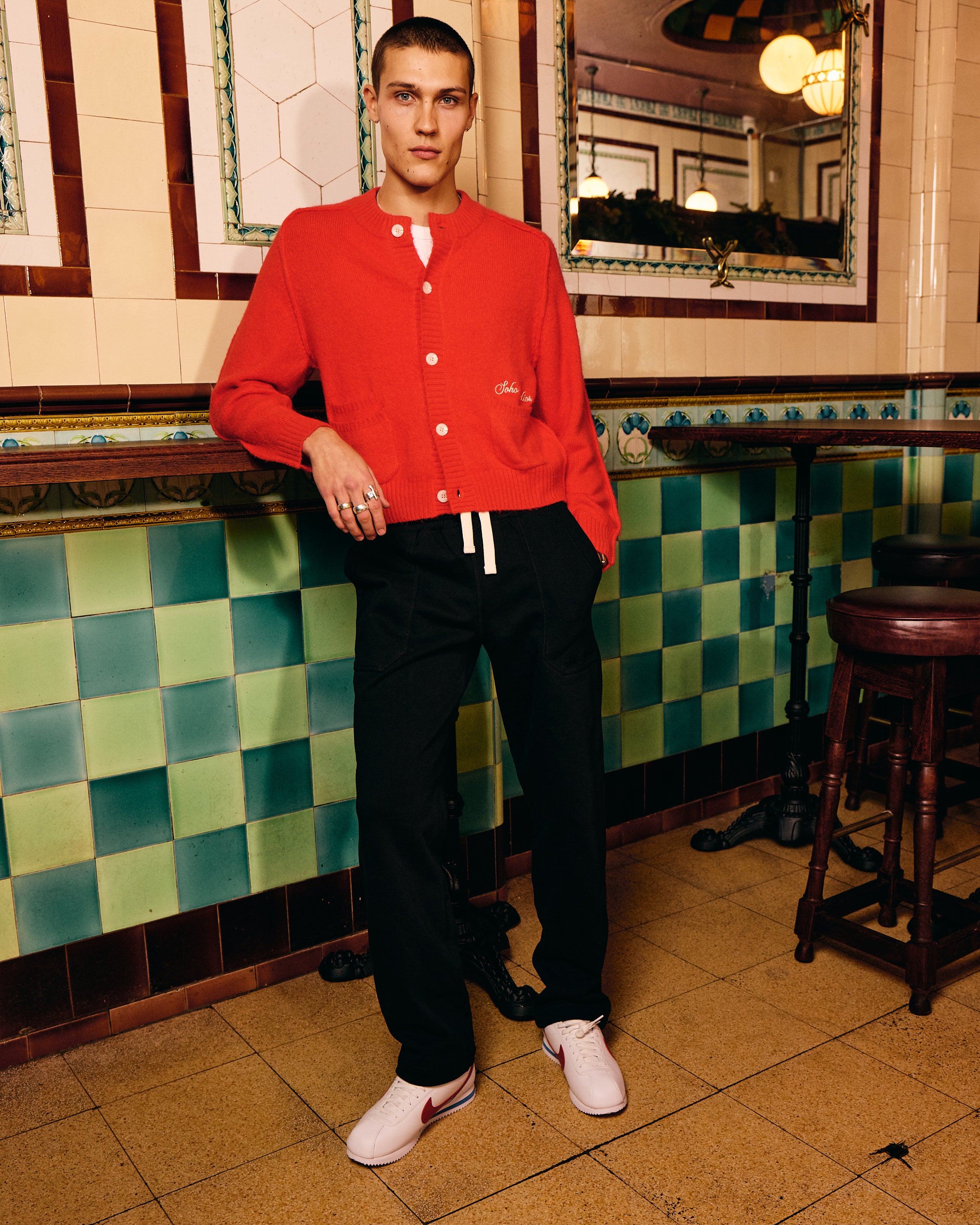 Person wearing a red jacket in a tiled room with a mirror.