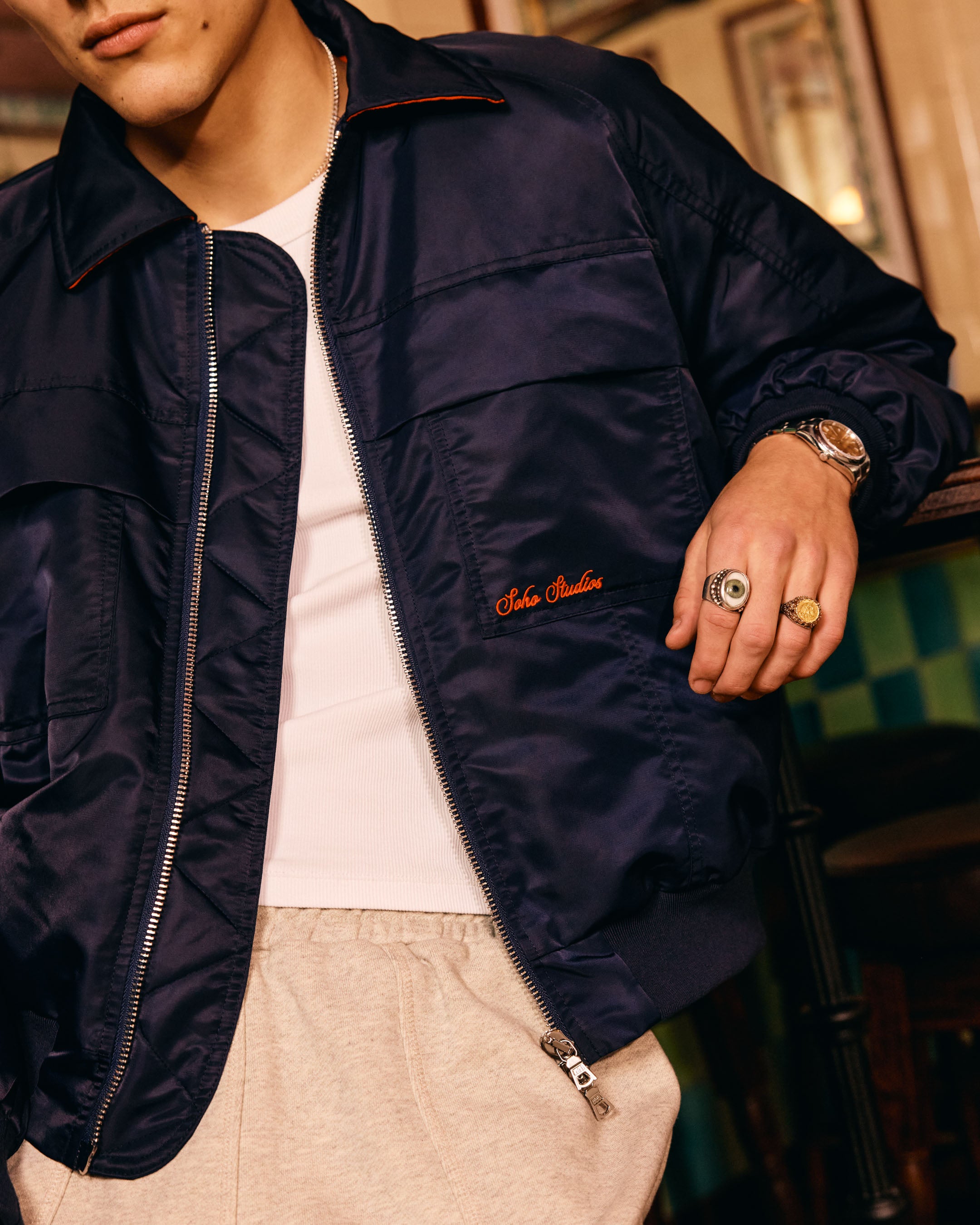 Person wearing a navy jacket with a brand logo, in an indoor setting.