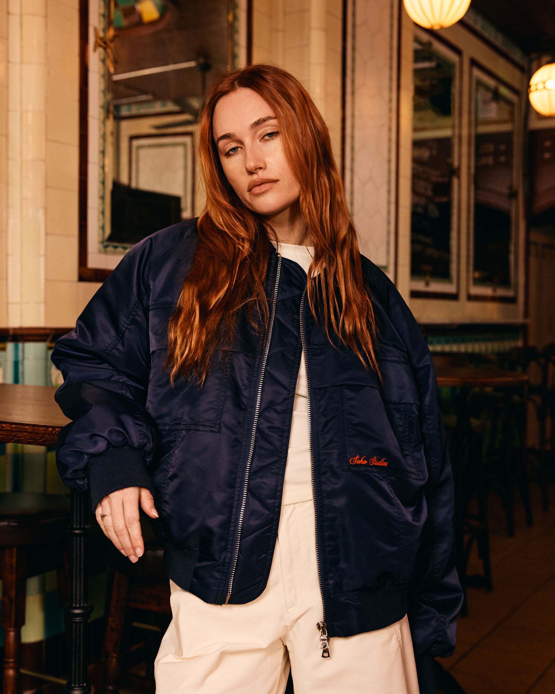 Woman wearing a navy bomber jacket in an indoor setting