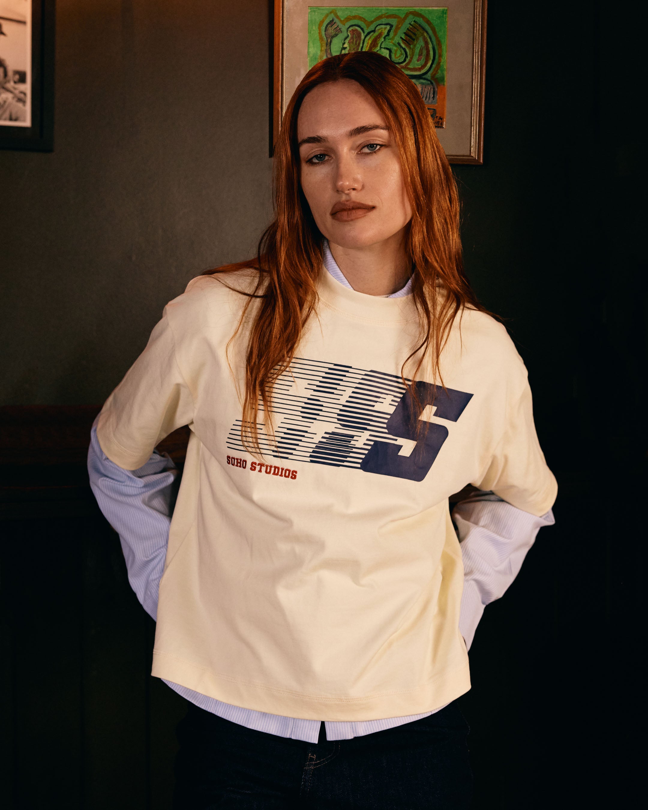 Person wearing a beige sweatshirt with a Soho Studio logo in an indoor setting