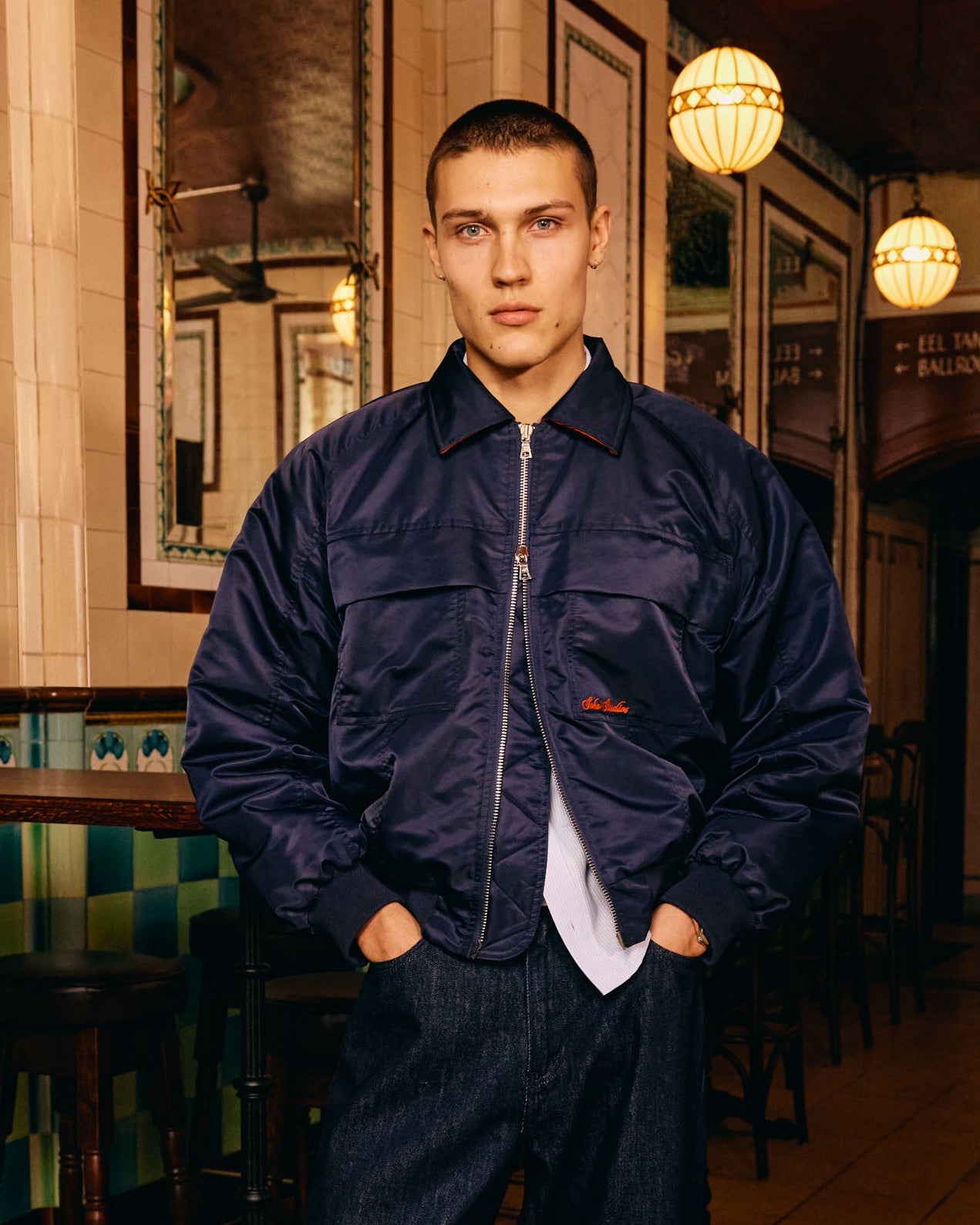 Man wearing a navy blue jacket in a bar setting