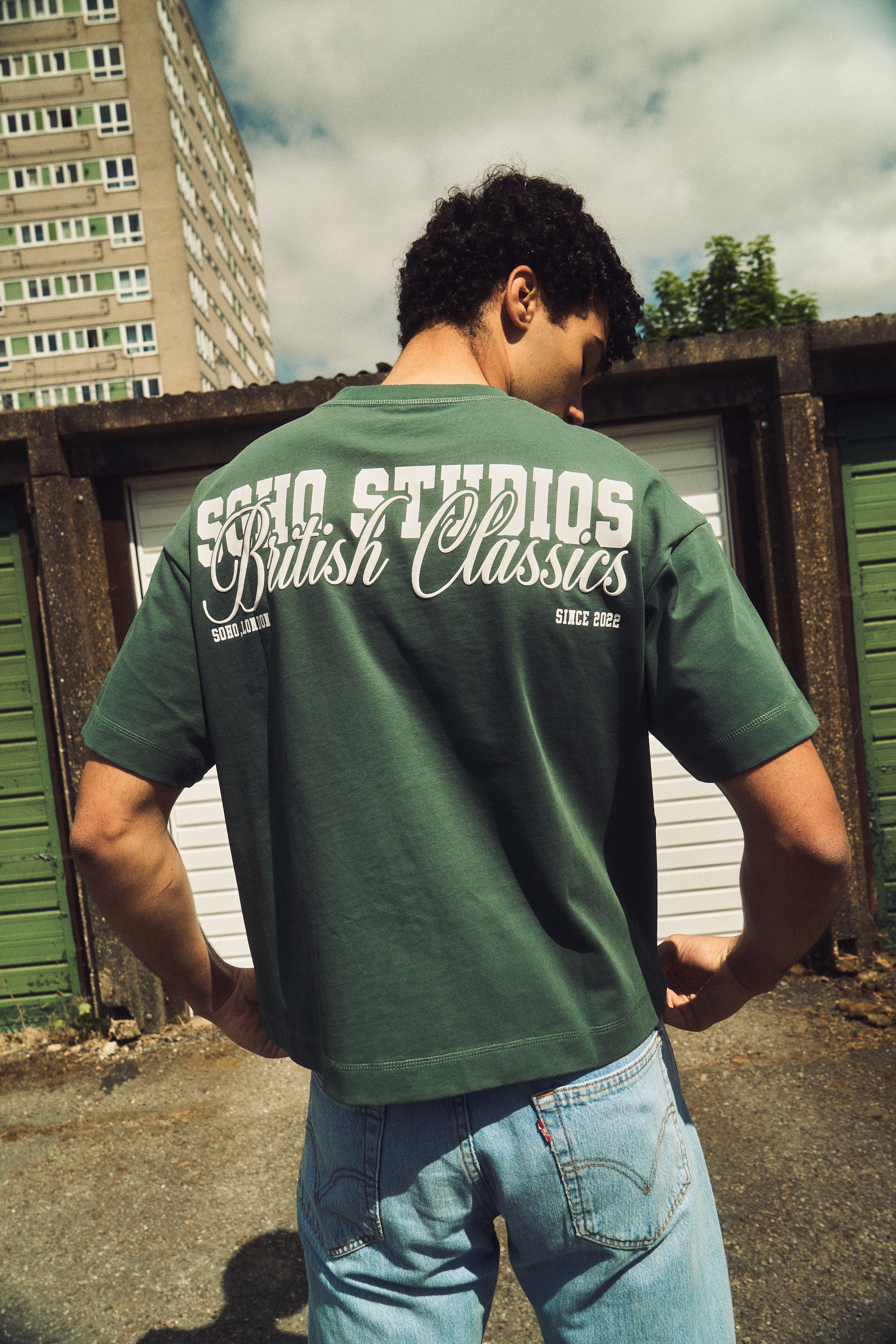 Person wearing a green t-shirt with text on the back, standing outdoors.
