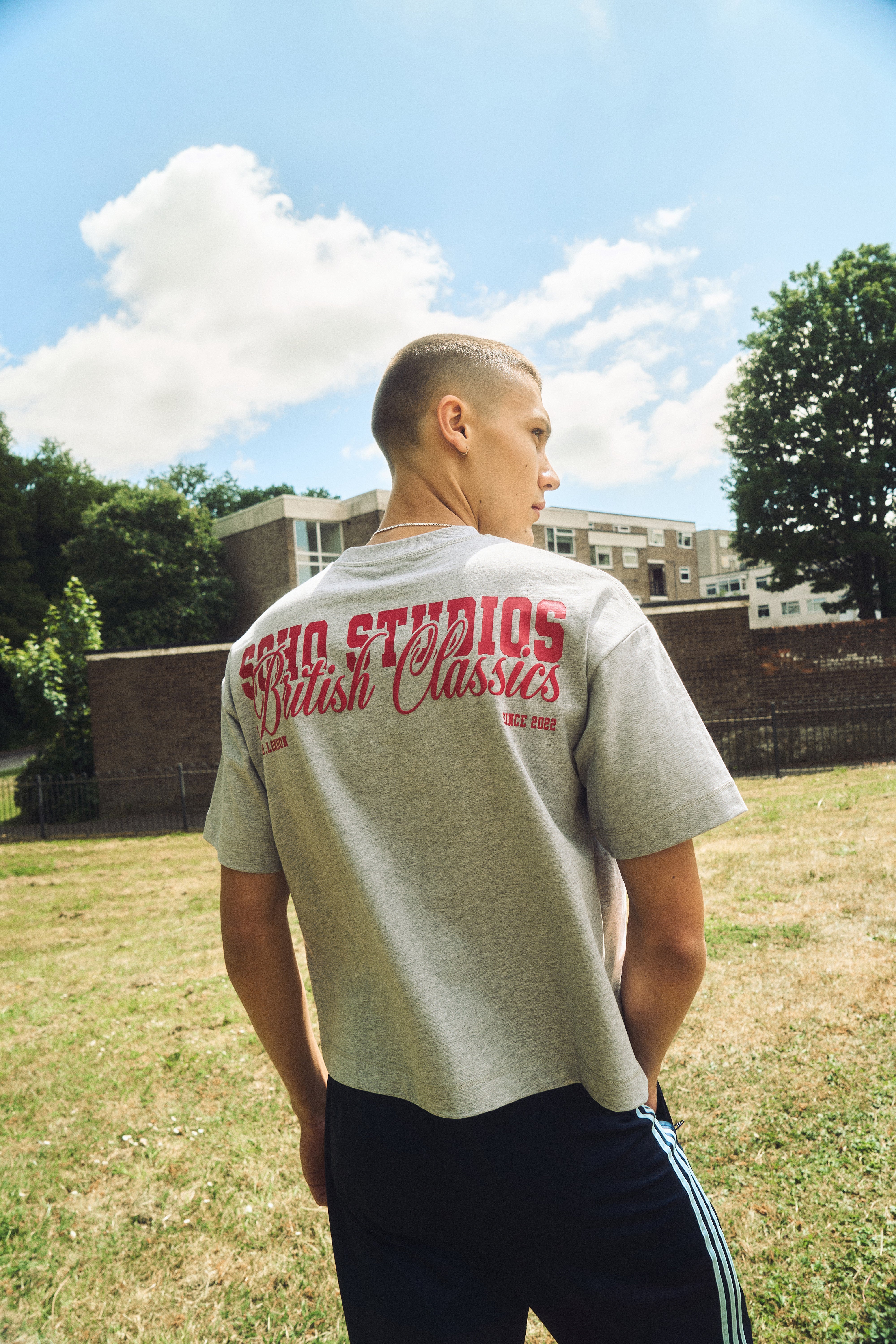 Person wearing a gray t-shirt with red text in an outdoor setting
