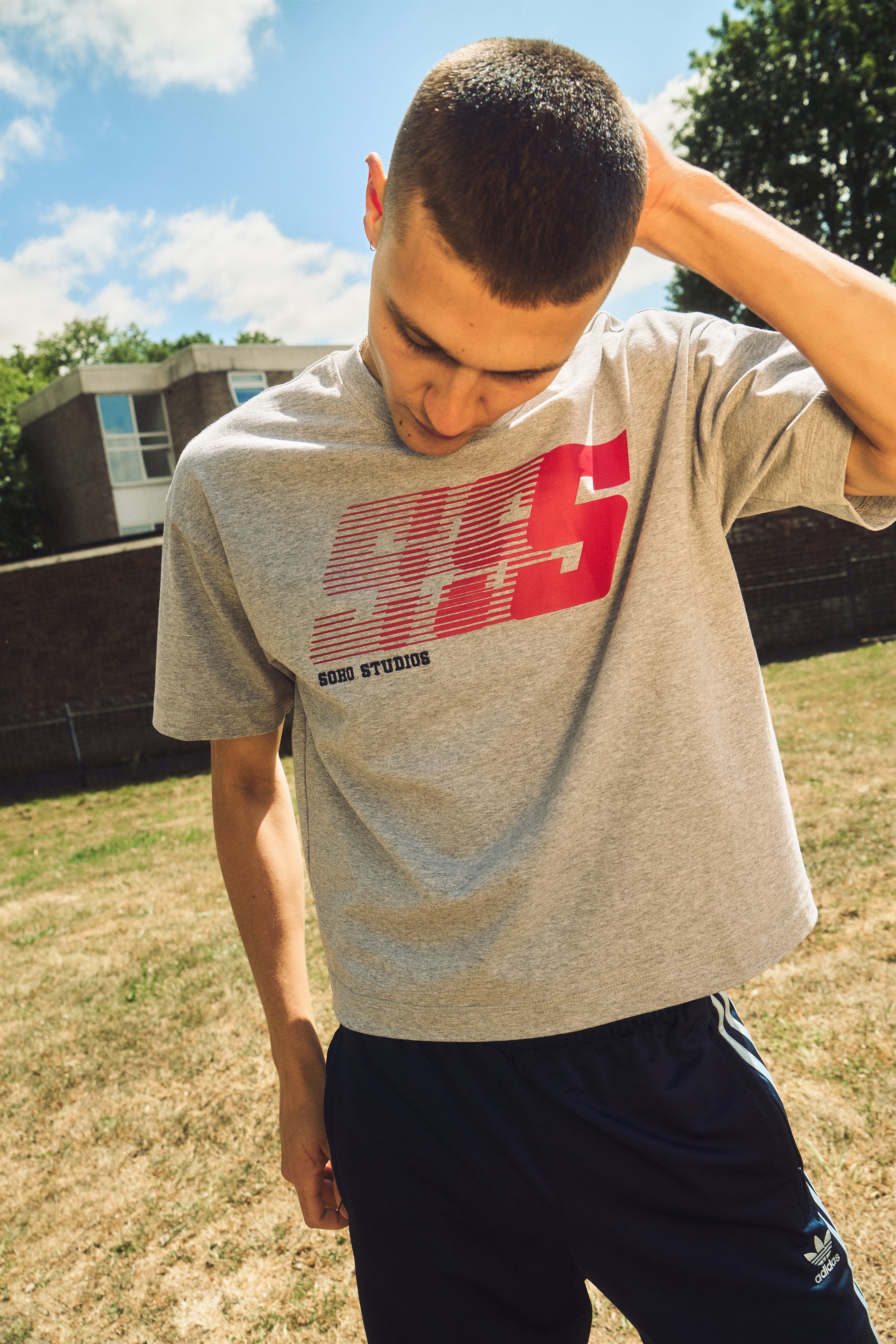 Man wearing a gray t-shirt with red and white text outdoors