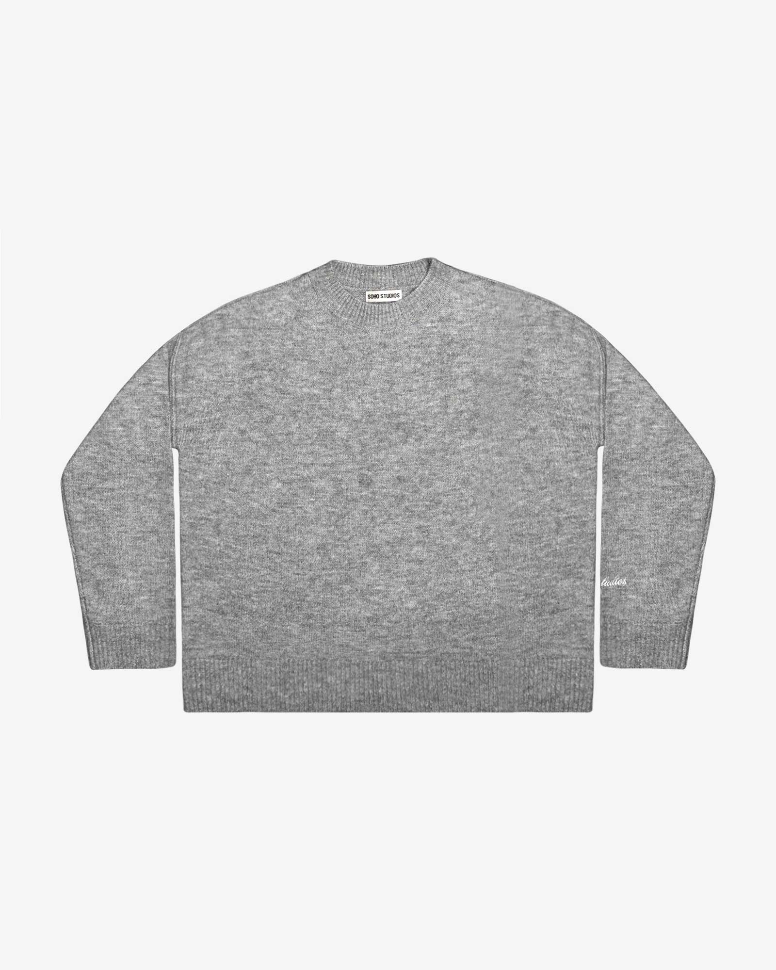 A gray 'SIGNATURE' knit sweater with reverse seam detailing and logo embroidery on the left sleeve, presented in a boxy and slightly cropped silhouette.