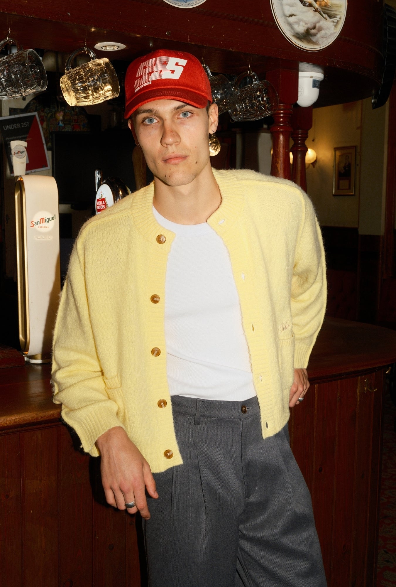 Person wearing a red cap and yellow cardigan in an indoor setting