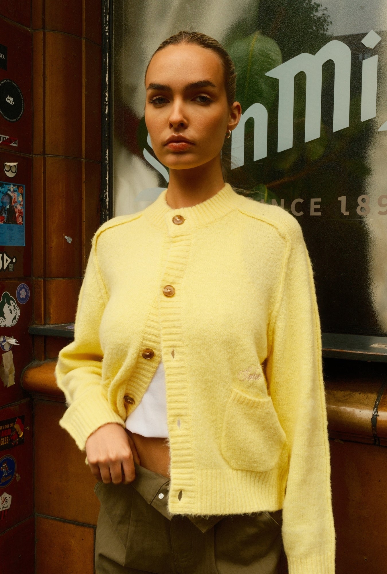 Person wearing a yellow cardigan in front of a store entrance